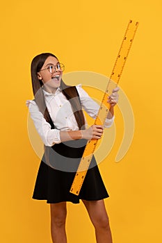 surprised nerd teen girl in uniform and glasses hold mathematics ruler for measuring, back to school