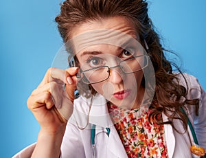 Surprised paediatrician doctor looking in camera on blue photo