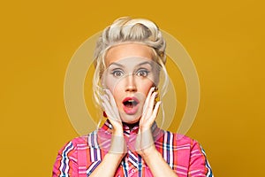 Surprised Pinup woman retro girl with red lips makeup and vintage fashion hairstyle on colorful yellow background