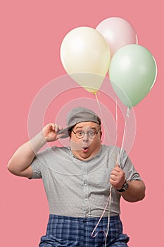 Surprised plump man with bugged eyes and rounded mouth, holding air balloons