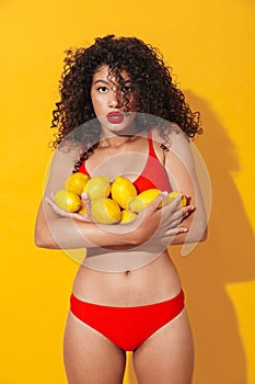 Surprised pretty young african woman holding lemons