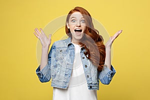 Surprised red hair teenage girl show shocking expression with something. Isolated on Bright Yellow Background. Copy