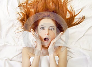 Surprised red-haired girl in bed