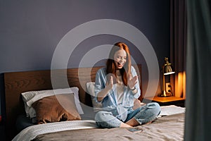 Surprised redhead young woman getting good online news on mobile phone.