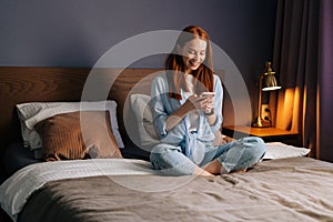 Surprised redhead young woman getting good online news on mobile phone.