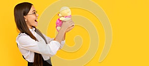 Surprised school age kid hold teddy bear yellow background, toy gift. Banner of child girl with toy, studio portrait