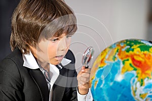 Surprised school boy with globe and lens