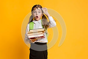 Surprised Schoolgirl Looking At Camera Holding Stack Of Books, Studio