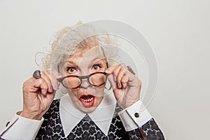 Surprised senior lady adjusting her glasses