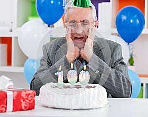 Surprised senior man looking at birthday cake