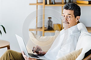Surprised senior man using laptop while sitting