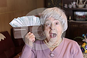 Surprised senior woman with full wallet