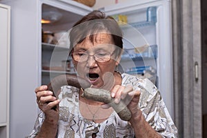 Surprised senior woman holding pork liver sausages