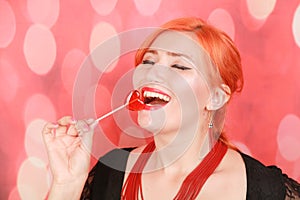 Surprised sexy girl eating lollipop. Beauty Glamour Model woman with heart shape red sweet.