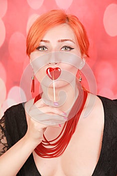 Surprised sexy girl eating lollipop. Beauty Glamour Model woman with heart shape red sweet.