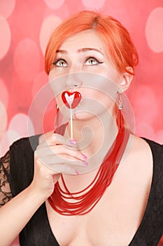 Surprised sexy girl eating lollipop. Beauty Glamour Model woman with heart shape red sweet.