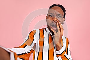 Surprised shocked afro-american man with dreadlocks in eyeglasses and stylish striped shirt looking at selfie camera with