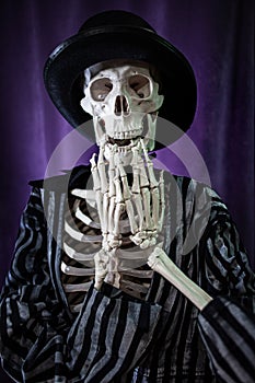 Surprised skeleton in a striped suit and top hat. Halloween