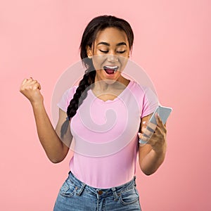 Surprised teen girl looking at smartphone, pink background