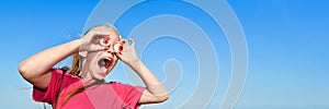 Surprised Teen girl in a pink t-shirt looks into the giant jelly eyes binoculars ahead. Banner with copy space.