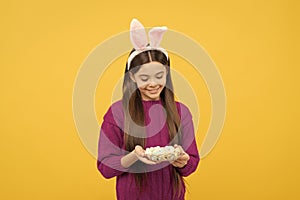 surprised teen kid in bunny ears with painted quail eggs for easter, easter egg