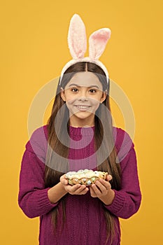 surprised teen kid in bunny ears with painted quail eggs for easter, easter egg