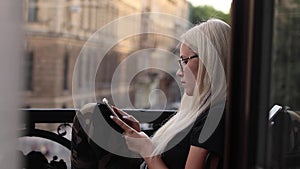 Surprised teenage girl finds internet content on a smartphone sitting on a balcony in a hotel