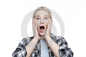 Surprised teenage girl with her mouth open. A cute blonde with freckles on her face wearing a plaid shirt and a blue top. Close-up