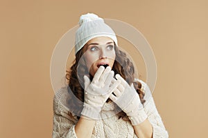 surprised trendy woman in beige sweater, mittens and hat