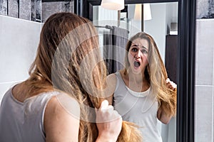Surprised unhappy young woman checking her dry tousled long hair photo