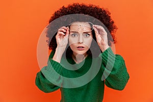 Surprised woman with Afro hairstyle wearing green casual style sweater standing raised her