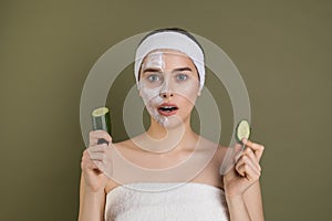 Surprised woman with bare shoulders loking at camera with open mouth, white mask on half of her face