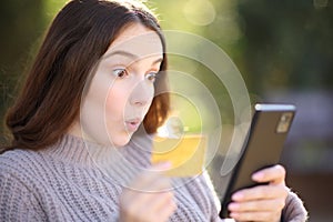 Surprised woman buying online in a park