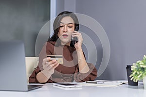 surprised woman calling by phone and holdind credit card to online shopping