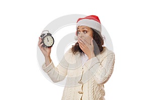 Surprised woman expresses astonishment stupefaction, looking at retro black alarm clock showing midnight. Happy New Year
