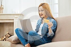 Surprised woman holding a card and looking at the screen