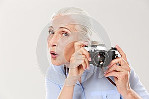 Surprised woman holding retro camera islated over white