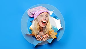 Surprised woman in knitted hat with autumn leaves looking through paper hole. Autumn sales. Discount. Season sales