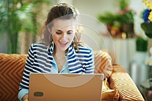 Surprised woman with laptop in modern house in sunny day