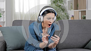 Surprised woman listening to music from cell phone