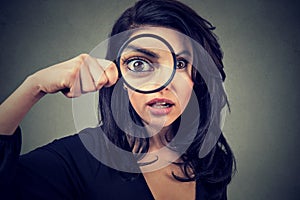 Surprised woman looking through magnifying glass