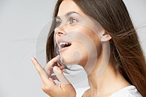 Surprised woman with open mouth looks to the side showing thumb up