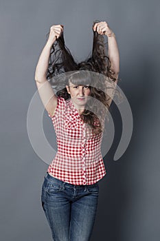 Surprised woman pulling out her long curly brown hair