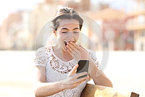 Surprised woman reading amazing news on a phone