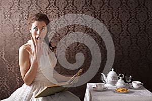 Surprised woman reading a book at tea time