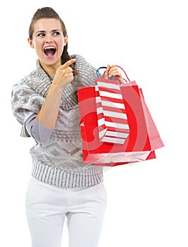 Surprised woman with shopping bags pointing on copy space