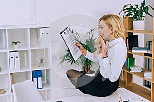 surprised woman sitting on table and looking