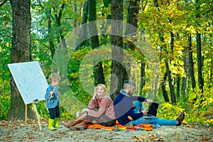 Surprised woman smile and looks up in the sky. Cheerful family sitting on the grass during a picnic in a autumnal park