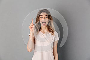 Surprised woman in t-shirt having idea and looking at camera