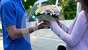 Surprised woman taking bouquet from couriers hands, flower shop delivery